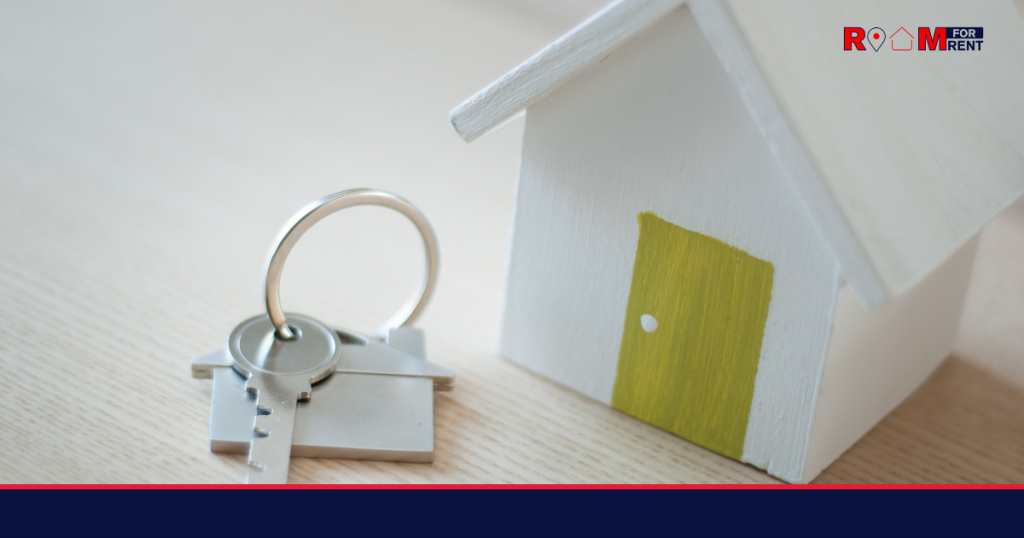 White wooden house on table with room keys on a keyring