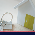 White wooden house on table with room keys on a keyring